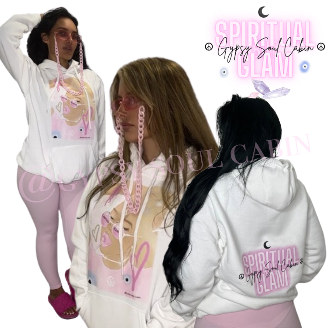 Back view of a white oversized hoodie featuring a pink "Spiritual Glam" logo, a small moon graphic, and "Gypsy Soul Cabin" text, worn by a woman with long black hair, with a similar hoodie worn by the woman with a graphic on the front.
