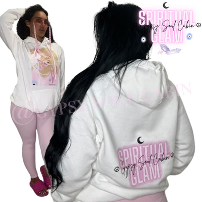 White oversized hoodie featuring a colourful graphic of a girl with sunglasses, surrounded by pink hearts and peace symbols, with "Spiritual Glam" text and the brand name "Gypsy Soul Cabin" on the back, with drawstrings and a front pocket.