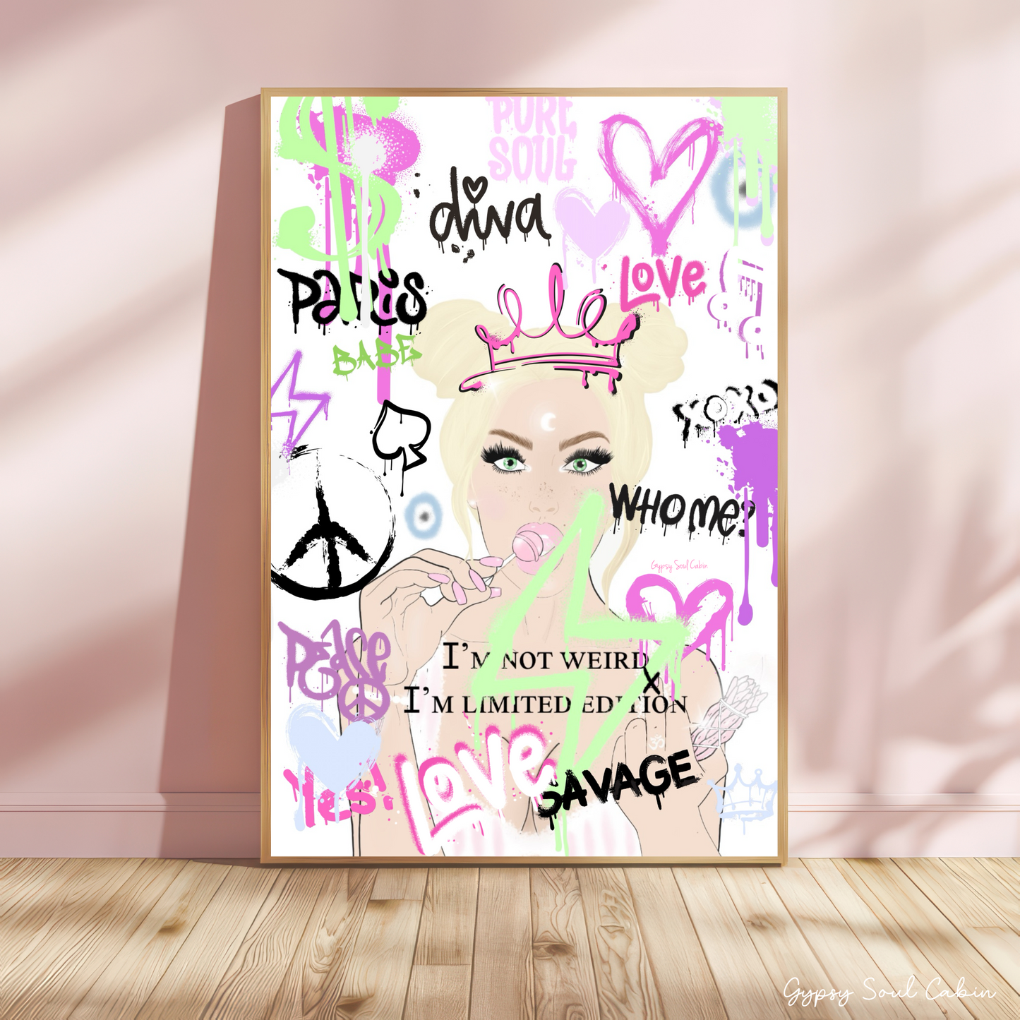 Illustrated pink graffiti girl quote print in a gold frame leaning against a white studio wall background.