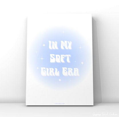Clean modern wall art print featuring a soft baby blue aura gradient background with stacked wavy white lettering reading In My Soft Girl Era.