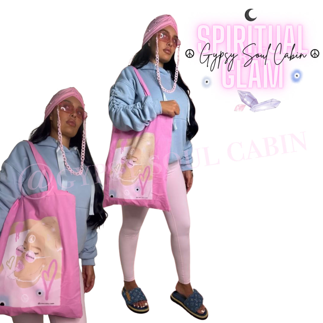 Bright pink canvas tote bag featuring an artistic female graphic print with hearts and an evil eye, paired with a light blue Gypsy Soul Cabin hoodie.