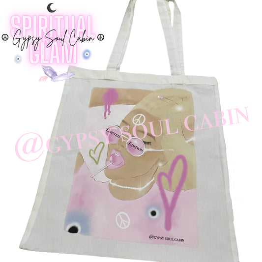 Close-up view of a white canvas tote bag displaying a detailed female art print with a pink lollipop, peace symbol, and heart illustrations.
