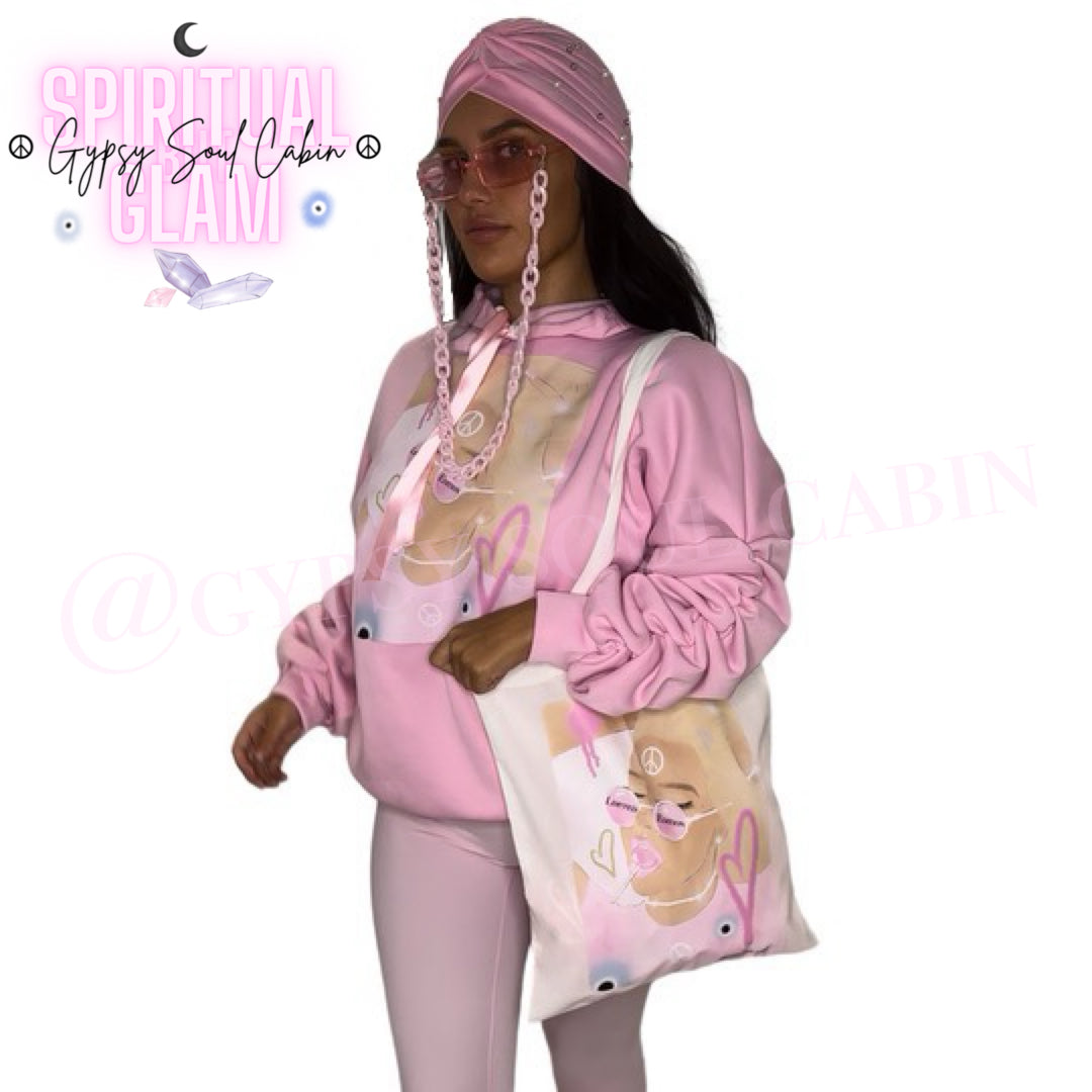 White canvas tote bag featuring an artistic female graphic wearing Limited Edition sunglasses and eating a pink lollipop paired with a pink Gypsy Soul Cabin hoodie