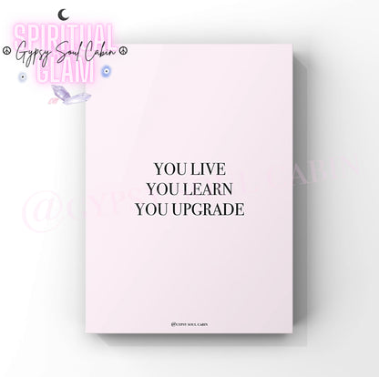 Empowering growth mindset wall decor print featuring the motivational slogan “You live, you learn, you upgrade” in clean black typography over a soft pastel pink setting